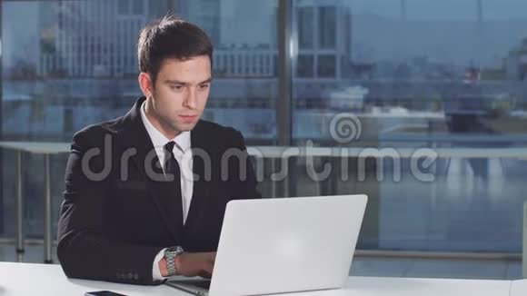 正经帅哥用笔记本电脑对着显示器屏幕工作视频的预览图
