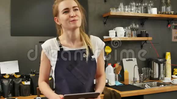 一位漂亮的女咖啡师拿着平板电脑和微笑的顾客点餐的画像视频的预览图