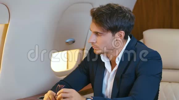 英俊的有钱人坐私人飞机飞行年轻自信的商人穿着西装在商务舱飞行视频的预览图