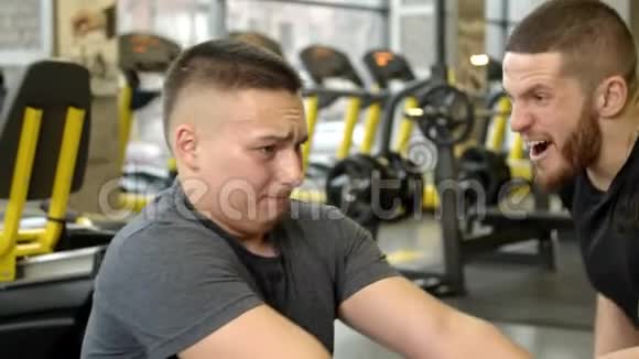一个年轻人在健身房锻炼时被教练喊着视频的预览图