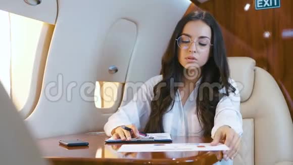 商务女士在飞机飞行时处理纸质文件女商人乘坐私人飞机旅行富人视频的预览图