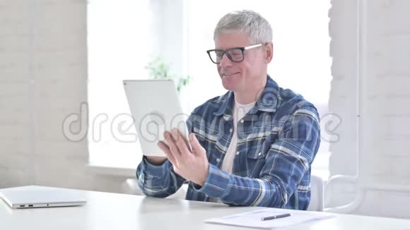 勤劳的休闲中年男子使用平板电脑视频的预览图