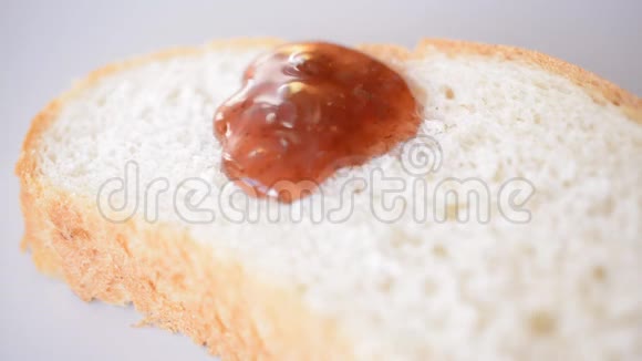 草莓果酱特写滴在面包上视频的预览图