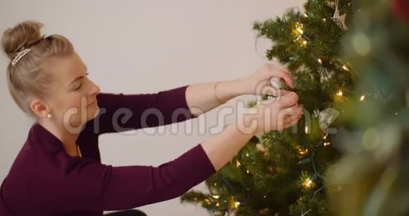女人用装饰品和灯光装饰圣诞树视频的预览图