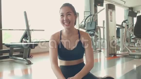 穿着运动服的快乐亚洲女孩在健身运动场地做瑜伽姿势后微笑着放松视频的预览图