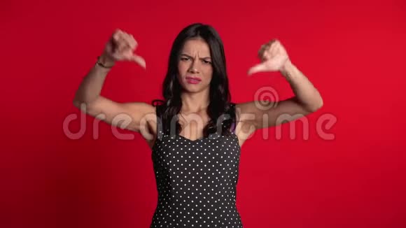 站在红色背景下的女人表示不满用拇指向下做手势视频的预览图