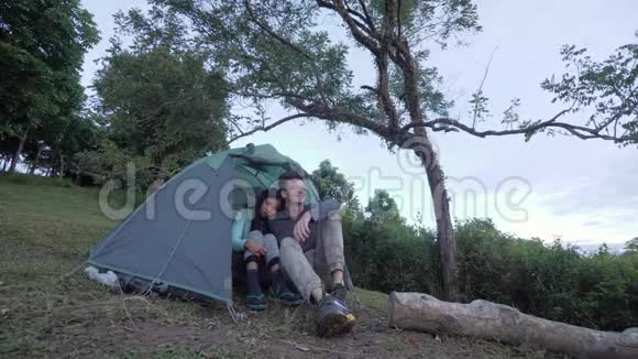 一对快乐的跨种族夫妇在大自然中的浪漫露营约会视频的预览图
