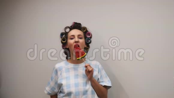 女人舔糖果年轻风趣的女孩用糖果贴着白墙视频的预览图