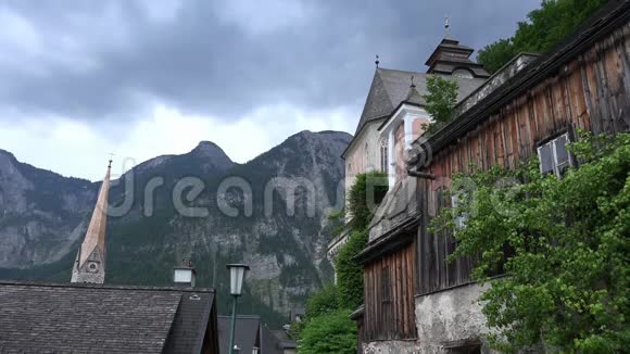 在奥地利达赫斯坦萨尔茨卡梅尔古特山谷著名的哈尔斯塔特村城市屋顶和教堂上空的云层消失视频的预览图