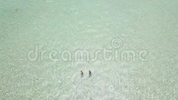 空中镜头的男子游客在岛上度假胜地游泳在晶莹剔透的海洋视频的预览图
