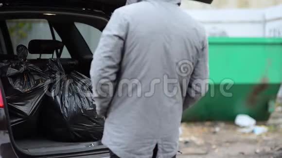 男人把垃圾袋从他的越野车后备箱扔进垃圾桶视频的预览图