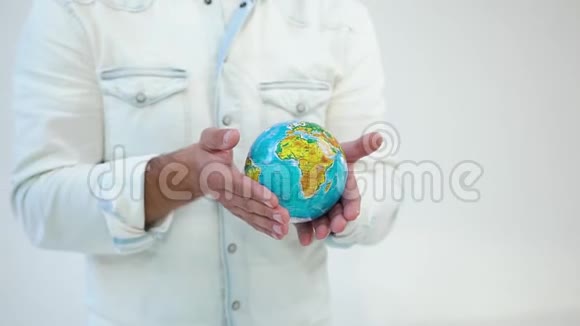 不知名的衣着光鲜的人手里拿着白色背景的地球模型视频的预览图