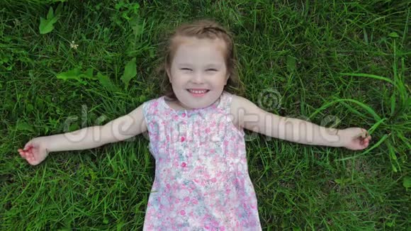 穿着裙子的小可爱女孩躺在草坪上微笑着视频的预览图