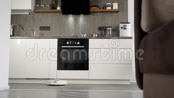 在时尚的现代厨房里打扫卫生自动机器人吸尘器沿着其轨迹移动a的要素视频的预览图