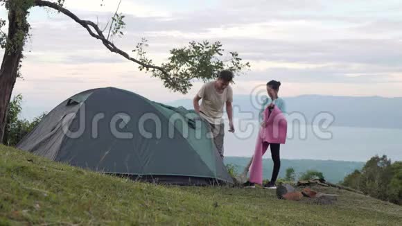 男人和女人在山上一个美丽的露营地点搭帐篷视频的预览图