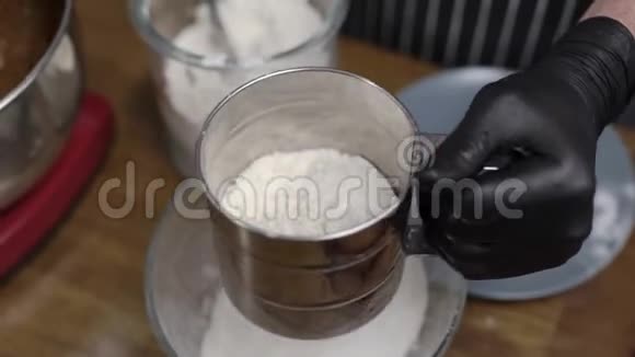 糕点厨师把面粉筛透戴着黑手套和坐椅的双手烹饪视频的预览图