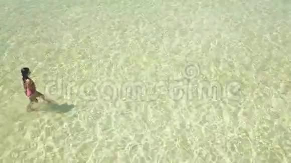 一个游客在一件泳装中的顶部侧面视图在晶莹剔透的水中行走视频的预览图