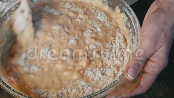 在家庭厨房的透明容器中用特制的木制烤勺揉制家庭面团视频的预览图
