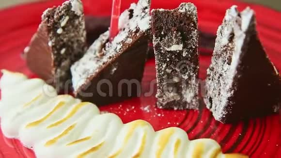 最新流行的装饰切片巧克力饼与烘焙奶油旋转在红色盘子视频的预览图