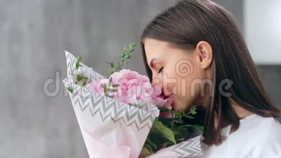 微笑着美丽的少女闻着一束清新的芳香花朵有着积极的情感视频的预览图