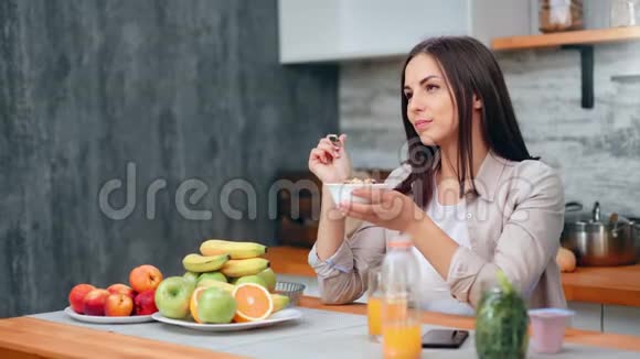 早晨女性在家厨房里吃早餐轻松地微笑着视频的预览图