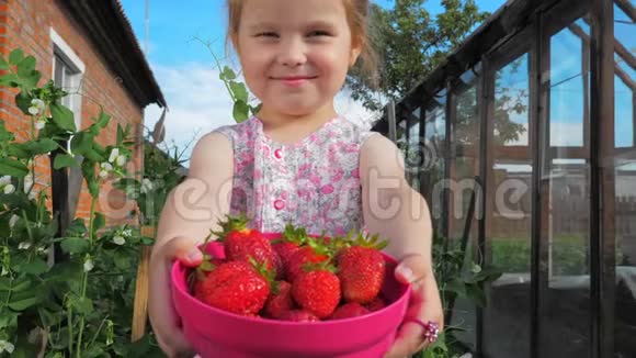 小可爱的漂亮女孩在伸出的手上拿着一个装满草莓的容器视频的预览图