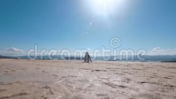 阳光明媚的一天美丽年轻的亚洲女孩坐在白沙滩上视频的预览图