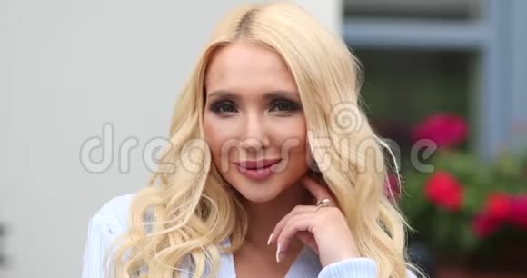 可爱的年轻的欧洲金发女人的肖像化妆微笑着摆着相机视频的预览图