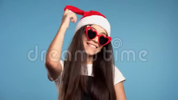 圣诞老人帽子和心形太阳镜的迷人女孩庆祝圣诞节视频的预览图