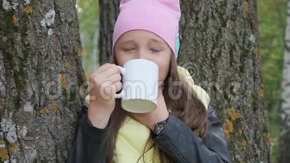 小十几岁的女孩喝热茶疼喉咙痛在秋天的森林里恶心的小女孩视频的预览图