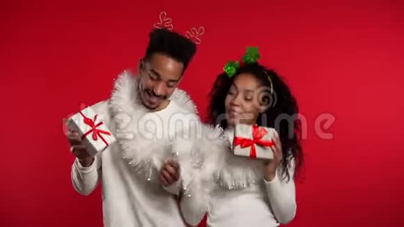 年轻的非裔美国人夫妇带着圣诞礼品盒跳舞被隔离在红色中视频的预览图