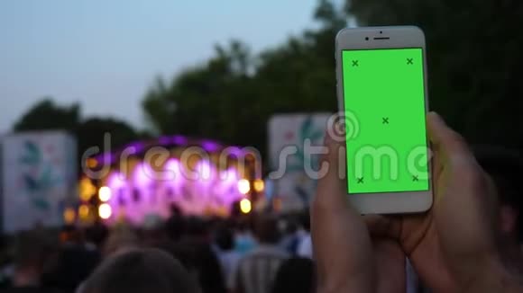 手中的年轻人拿着电话录音视频在模糊的音乐会背景前视频的预览图