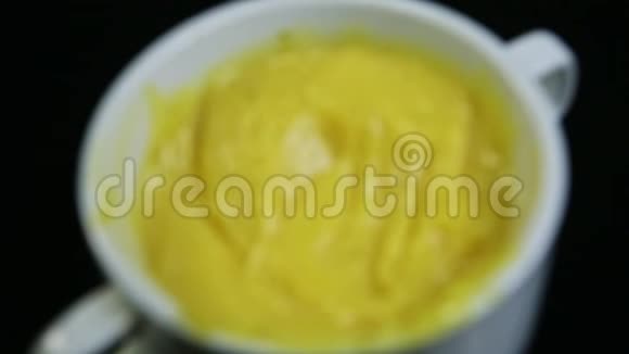 顶部观看特写镜头集中在白色杯子中的黄色奶油团视频的预览图