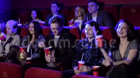 年轻的时髦朋友正在电影院看电影他们正在吃爆米花视频的预览图