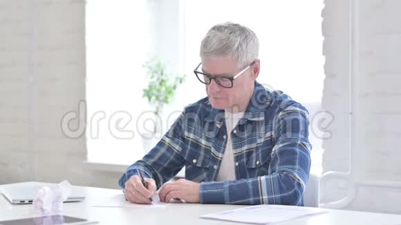 失望的休闲中年男子试图写在纸上视频的预览图
