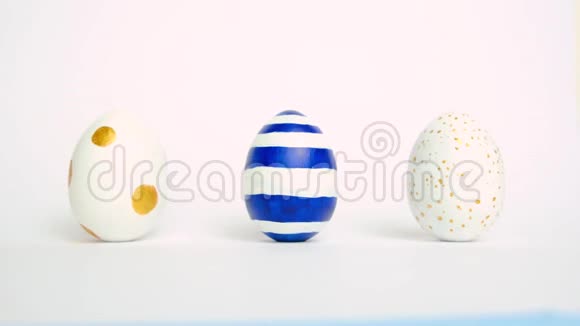 复活节彩蛋在滚动在白色的桌子上互相碰撞鸡蛋时髦的颜色经典的蓝色白色和金色快乐视频的预览图