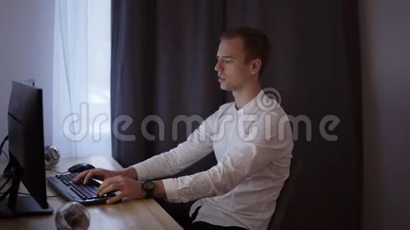 休闲商人在家工作坐在办公桌前在键盘上打字看电脑屏幕灰色窗帘视频的预览图