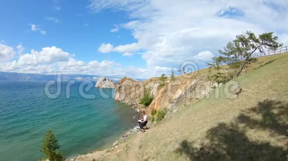 鸟瞰一个女孩坐在陡峭的河岸上画画美丽的风景视频的预览图