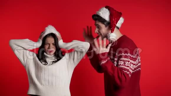 戴着圣诞帽的年轻人对着妻子或女友红色背景尖叫视频的预览图
