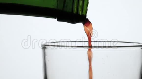 将果汁从绿色瓶中倒入玻璃中在白色背景上隔离视频的预览图