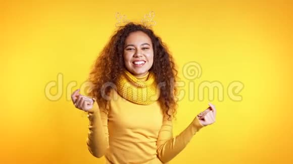 年轻可爱的女孩微笑着在黄色的工作室背景上跳舞戴鹿角的女人新年和圣诞节的心情视频的预览图