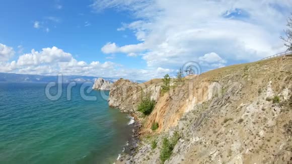 坐在悬崖上画画的女孩无人机飞过贝加尔湖的岩石海岸视频的预览图