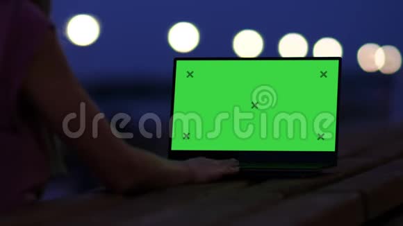 女人晚上看着户外的笔记本电脑屏幕视频的预览图