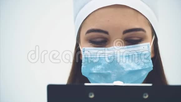 可爱的女治疗师站在医疗面具拿着剪贴板她读了一些好消息正在看视频的预览图