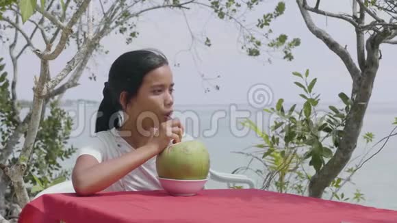 一位在热带度假胜地喝新鲜椰子汁的女士在享受放松的时光视频的预览图