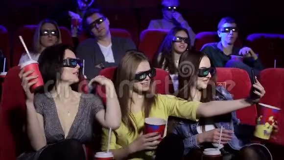 三个戴3D眼镜的年轻女孩在电影院里自拍视频的预览图