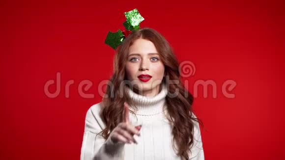 圣诞美女听到花圈在工作室的嘴唇上伸出手指视频的预览图
