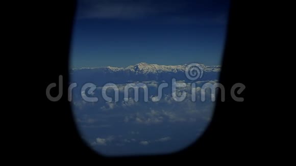 在雪山和云层上形成一个飞机窗口的视图视频的预览图