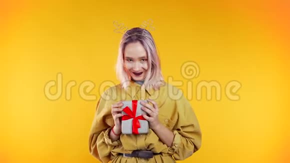 不寻常的女人粉红色的头发微笑送礼物把它放在黄色的相机上视频的预览图