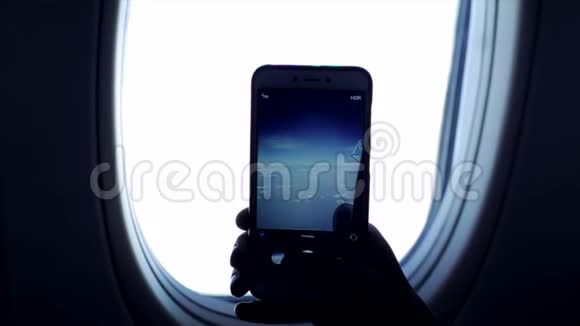 近距离观察一个人在飞机窗外用天空和云层的手机拍照视频的预览图